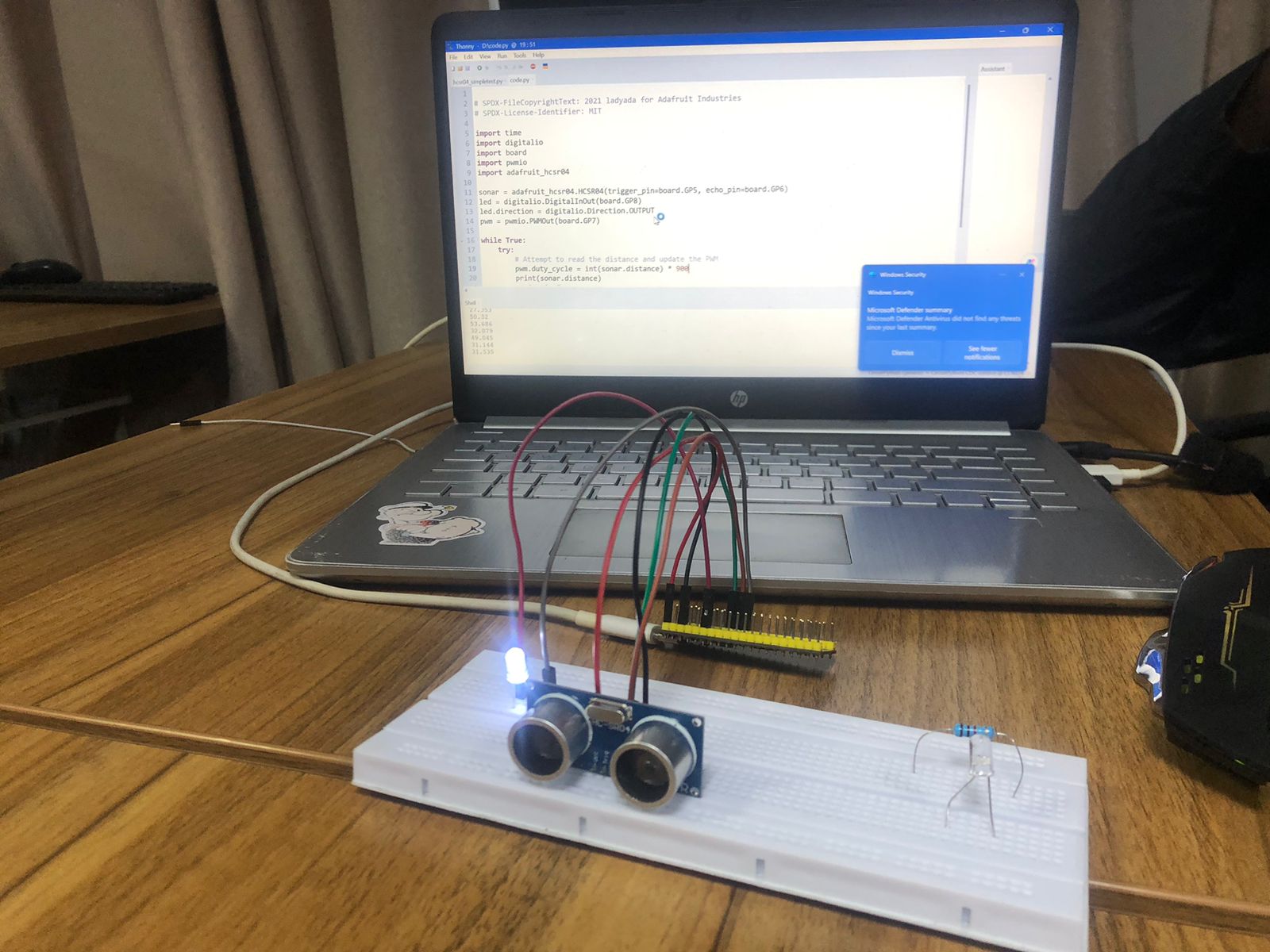 Laptop screen showing CircuitPython code alongside the active breadboard setup